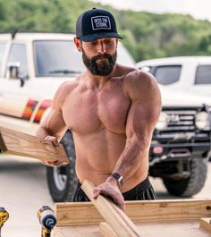 a shirtless man holding two pieces of wood