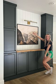 a woman standing in front of a painting on the wall next to a wooden floor