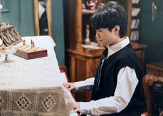 a young boy playing a piano in front of a table with chess pieces on it