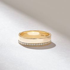 a yellow gold wedding band with diamonds on the outside and inside, sitting on a white surface