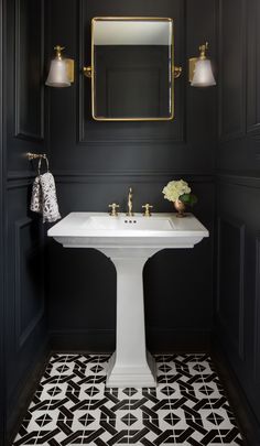 the bathroom is decorated in black and white, with gold accents on the mirror above the pedestal sink