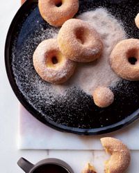 powdered donuts on a black plate with sugar sprinkled around them in the middle