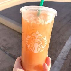 a hand holding up a drink with a straw in it's cup, on the street