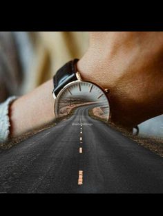 a person with a watch on their wrist standing in the middle of an empty road