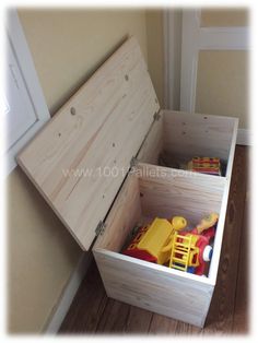 a wooden box filled with toys sitting on top of a hard wood floor next to a window