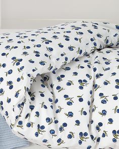 an unmade bed with blue flowers on it, and white sheets in the background