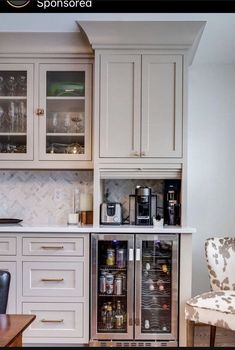 a kitchen with white cabinets and an open wine cooler in the corner, next to a dining room table