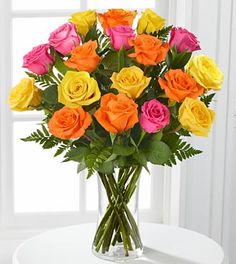 a vase filled with lots of different colored roses