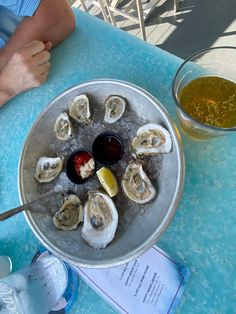 a plate of oysters on an ice bucket next to a glass of beer and sauce