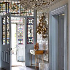 an entryway with stained glass doors and chandelier