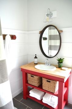 a bathroom with a sink, mirror and towels on the shelf in front of it