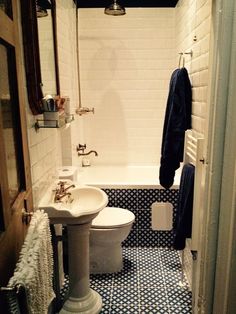 a white toilet sitting next to a bath tub in a bathroom on top of a blue and white floor