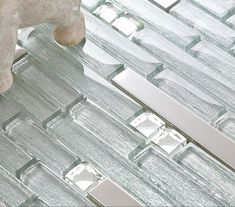 a white teddy bear sitting on top of a glass floor tile covered in silver squares