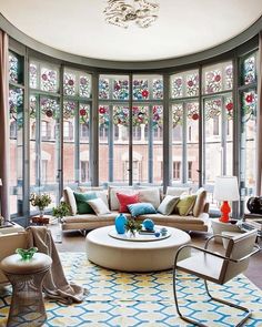 a living room filled with lots of furniture and large windows covered in stained glass panels