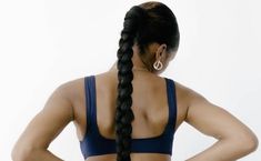 a woman with her back to the camera, wearing a blue sports bra and braided hair