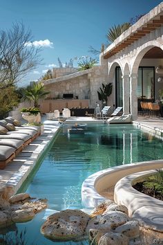 an outdoor swimming pool with lounge chairs around it and stone steps leading up to the house