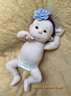 a baby doll with a blue flower on its head and diaper is laying down