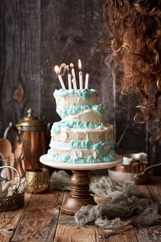 a blue and white cake sitting on top of a wooden table with candles in it