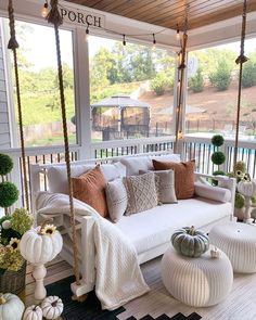 the porch is decorated with white furniture and pumpkins