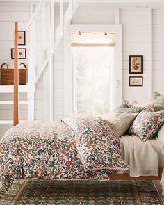 a bed sitting under a window next to a stair case in a room with white walls