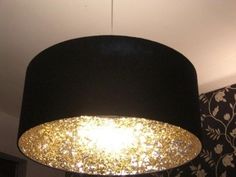 a black lamp shade with gold flecks hanging from it's ceiling in a living room