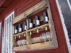 wine glasses are lined up in a wooden rack on the side of a red building