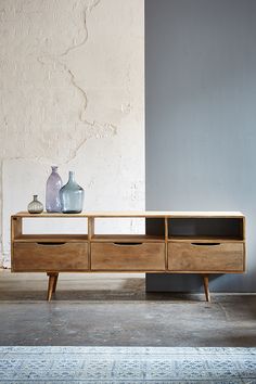 the sideboard has three drawers and two vases on it, along with a rug