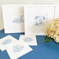 three framed pictures sitting on top of a table next to hydranges and flowers