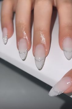 a woman's hand with white and silver nail polish on her nails, next to a computer keyboard