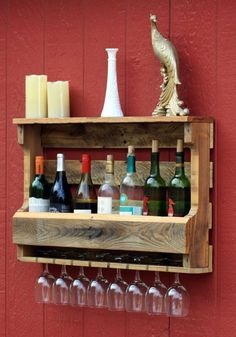 wine glasses and bottles are lined up on a wooden shelf in front of a red wall