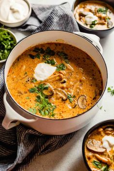 two bowls filled with mushroom soup on top of a white tablecloth next to other dishes