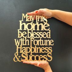 two hands holding up a piece of wood that says, may this home be blessed with fortune happiness and success