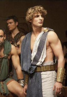 two men in roman costumes standing next to each other with one man wearing a towel