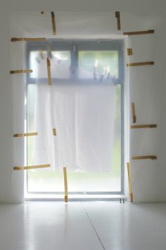 an empty room with white walls and yellow tape on the window sill, as seen from behind