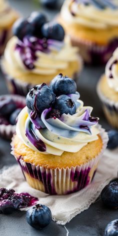 blueberry cupcakes with white frosting and fresh berries on the top, ready to be eaten