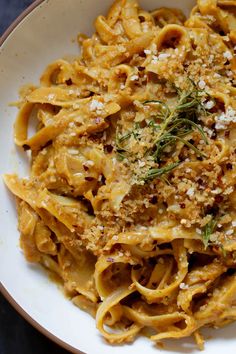 a white bowl filled with pasta covered in cheese and herbs