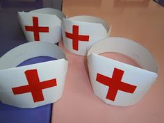 four paper bracelets with red crosses on them sitting on a pink counter top next to each other