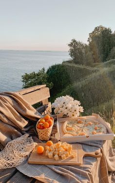 two trays of food sitting on top of a wooden bench next to the ocean