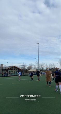 some people are playing soccer on a field with the sky in the back ground and clouds in the background