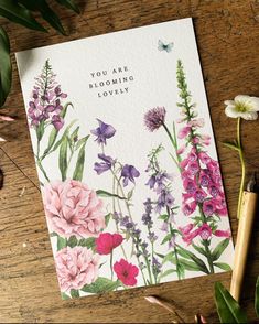 a card with flowers on it sitting next to some pencils