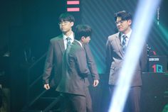 three young men in suits standing on stage