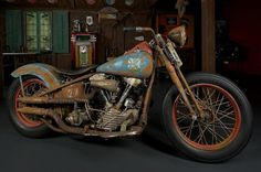 an old rusted motorcycle is parked in a room with other items on the walls