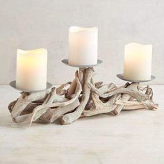 three white candles sitting on top of driftwood