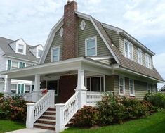 a large house with white railings and flowers in the front yard