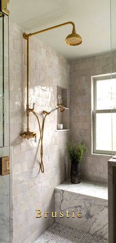 a bathroom with a shower head, window and tiled walls in gold trimmings