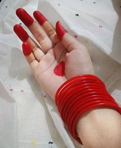 a woman's hand with red nails and bracelets on top of her arm