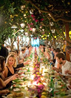 a long table full of people sitting at it with plates and glasses on the table