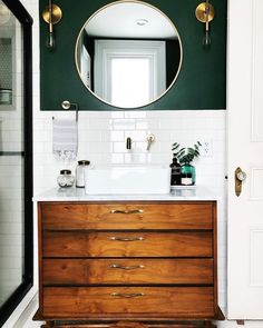 a bathroom with green walls and white tile on the floor, along with a wooden dresser