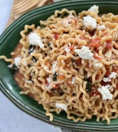 a green bowl filled with pasta and fettuccine on top of a table