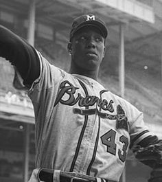 an old black and white photo of a baseball player holding his arm up in the air